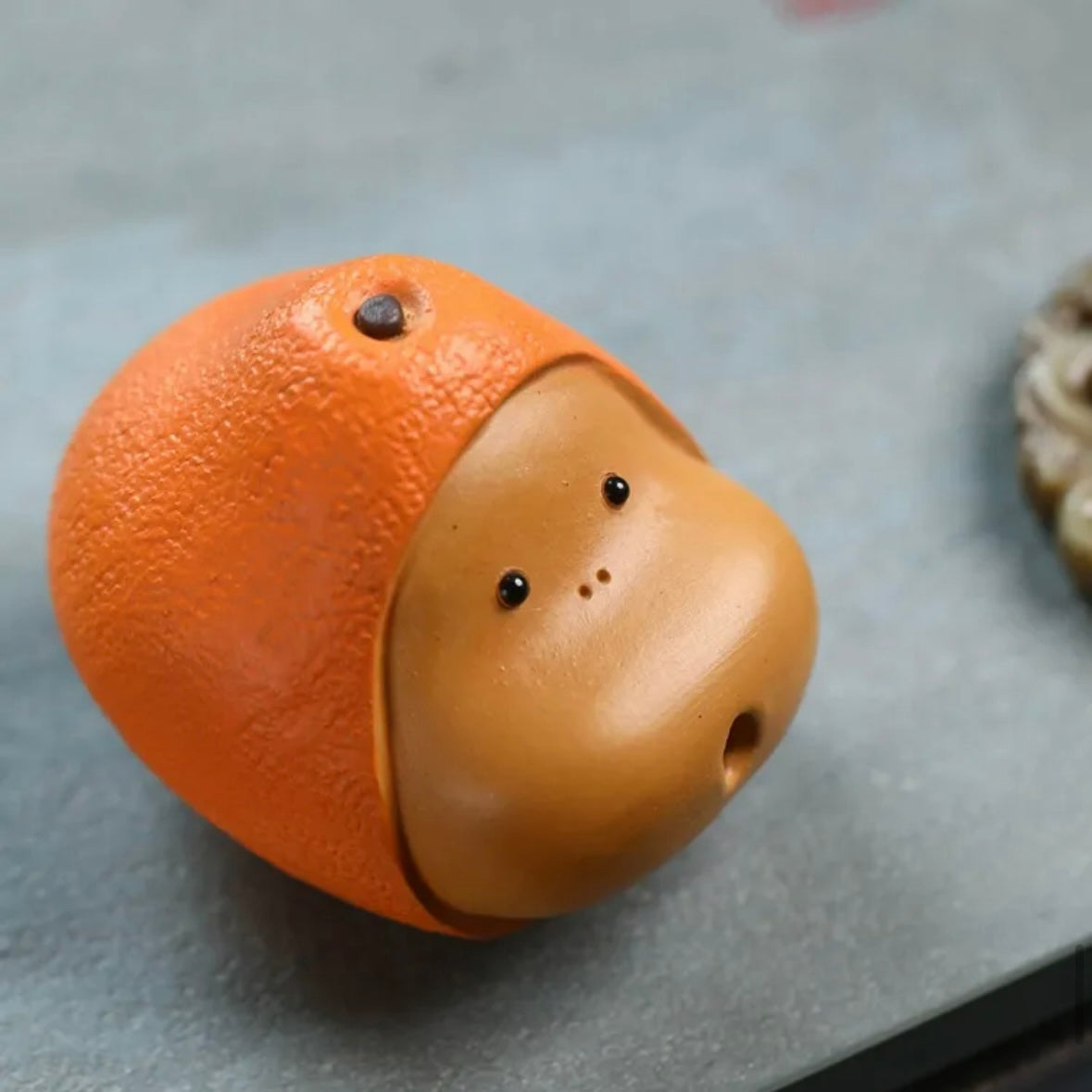 Orange Yixing tea pet crafted from purple clay, featuring a vibrant design ideal for traditional tea ceremonies and collections.