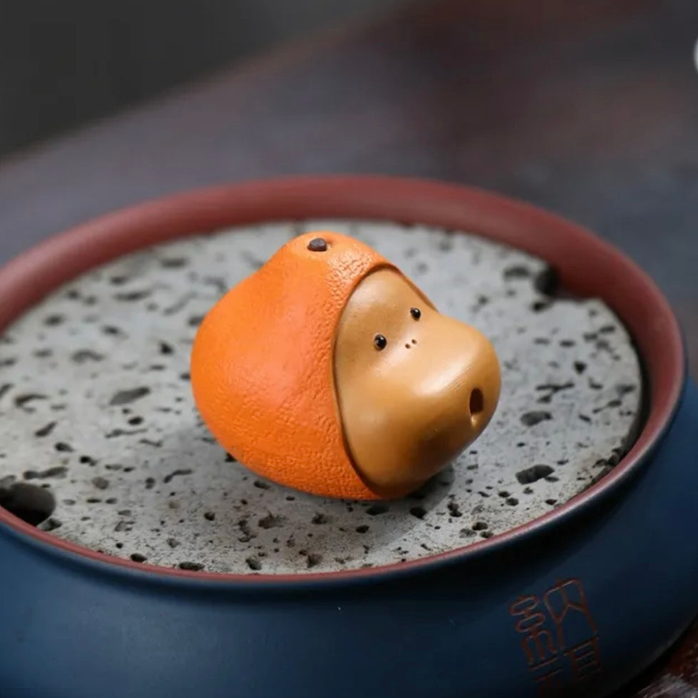 Orange Yixing tea pet crafted from purple clay, featuring a vibrant design ideal for traditional tea ceremonies and collections.