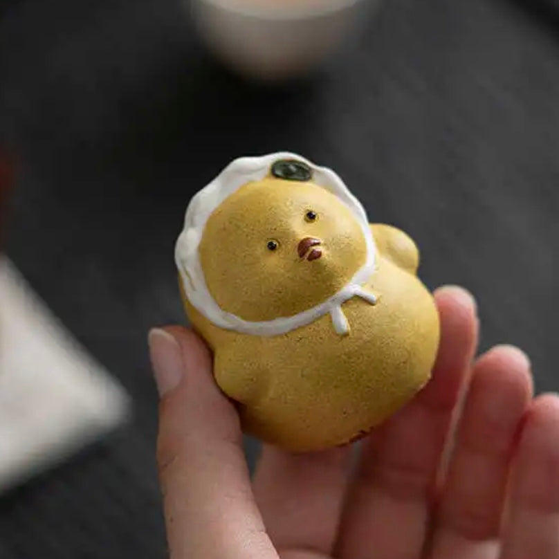 Yellow duck tea pet crafted from Yixing purple clay, combining playful design with traditional artistry for tea ceremonies.