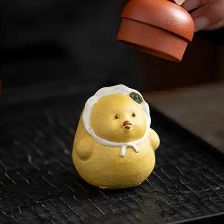 Yellow duck tea pet crafted from Yixing purple clay, combining playful design with traditional artistry for tea ceremonies.