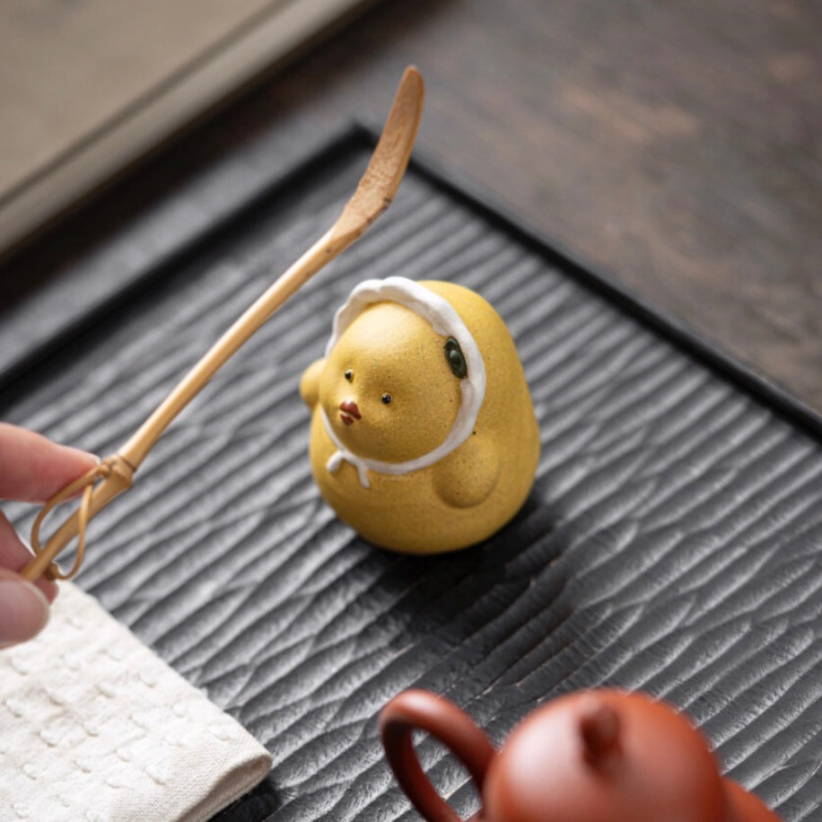 Yellow duck tea pet crafted from Yixing purple clay, combining playful design with traditional artistry for tea ceremonies.
